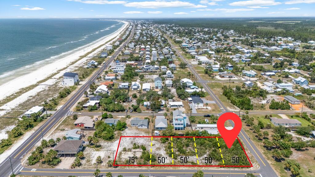 Aerial view of a marked vacant lot near the beach, with parcel dimensions and a red location pin.