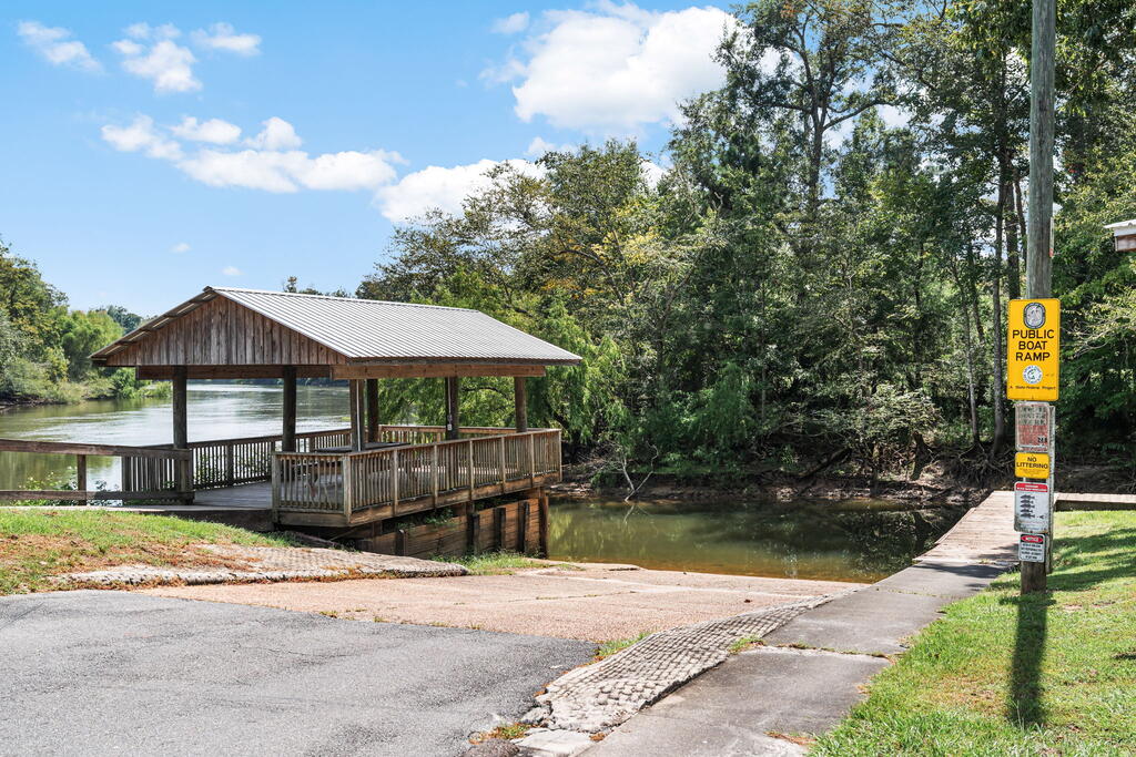 Covered wooden boat ramp beside a calm, tree-lined river.