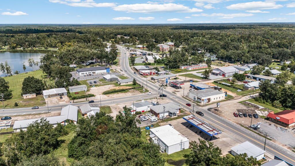 Aerial view of a commercial area with a main road, businesses, and a lake.
