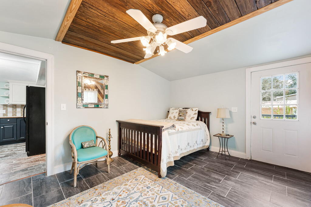 Bedroom with a dark wooden crib, turquoise chair, and wood-paneled ceiling.