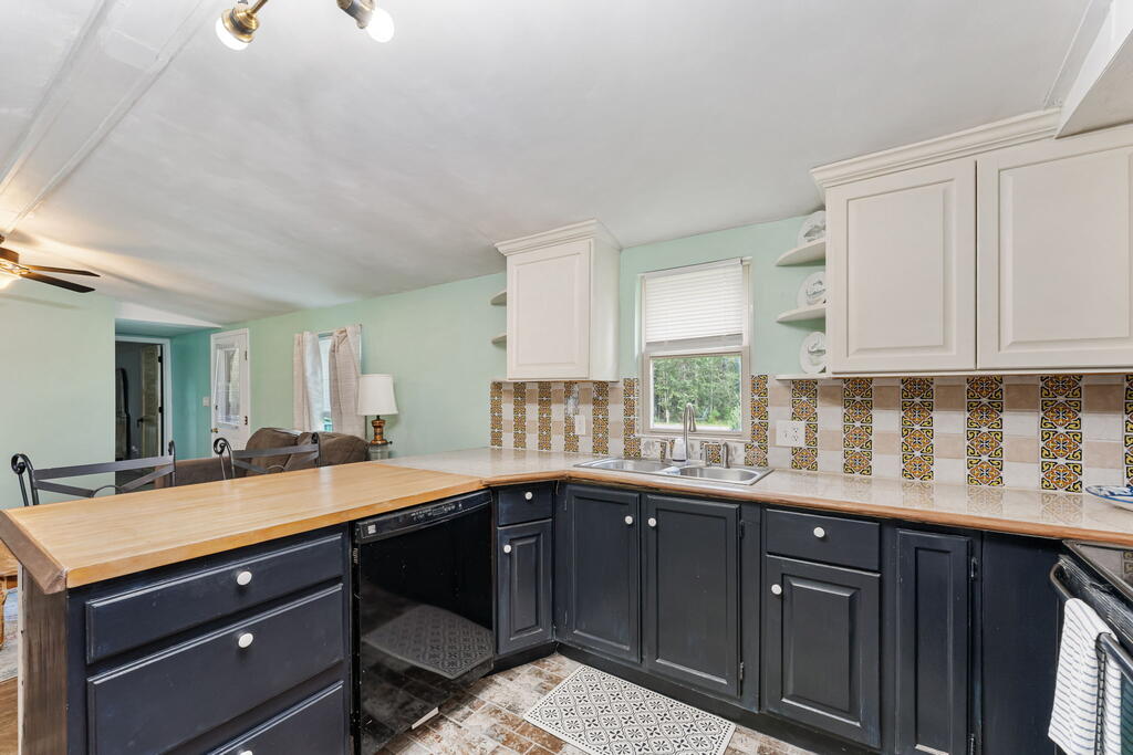 Kitchen with dark cabinets, a light wood countertop, and a colorful patterned tile backsplash.