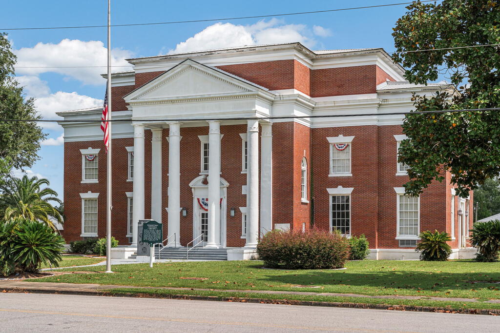 Red-brick civic building with a white-columned entrance and American flag.