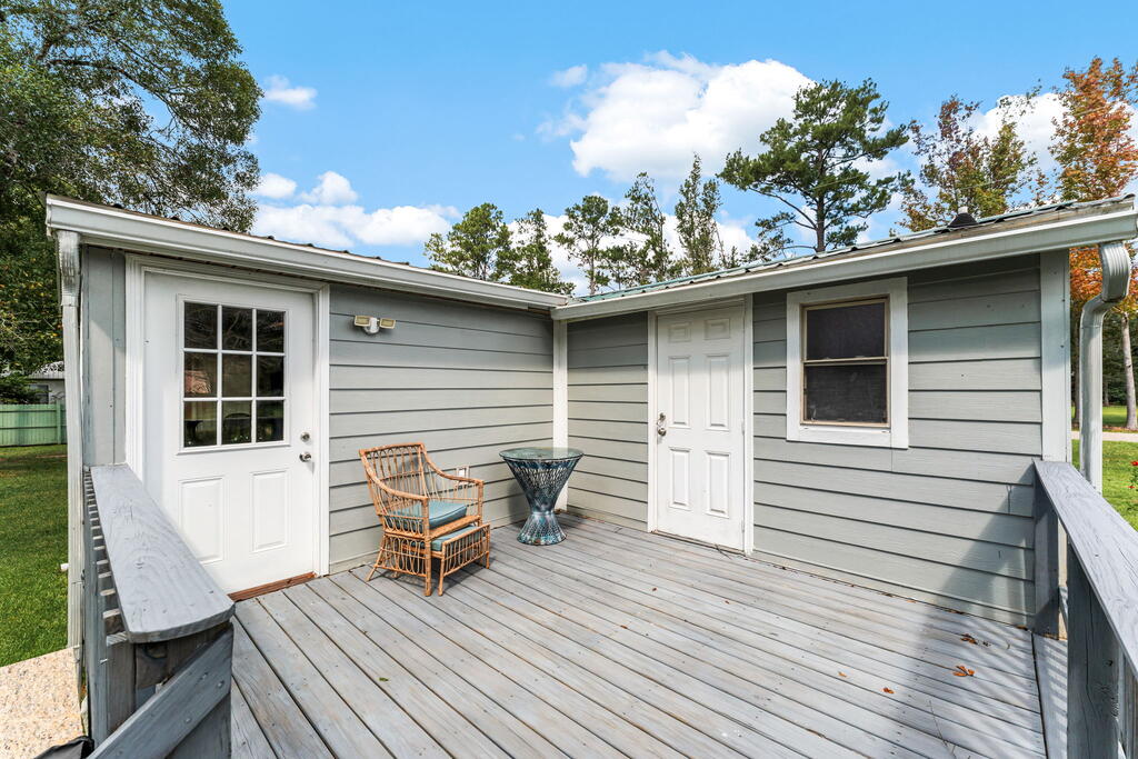 Raised gray deck with white doors, a wicker chair, and a small table.