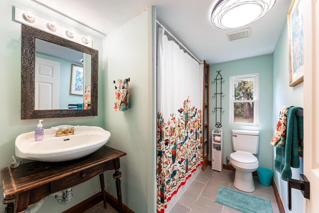 Bathroom with an aqua interior, floral shower curtain, and dark wooden vanity.