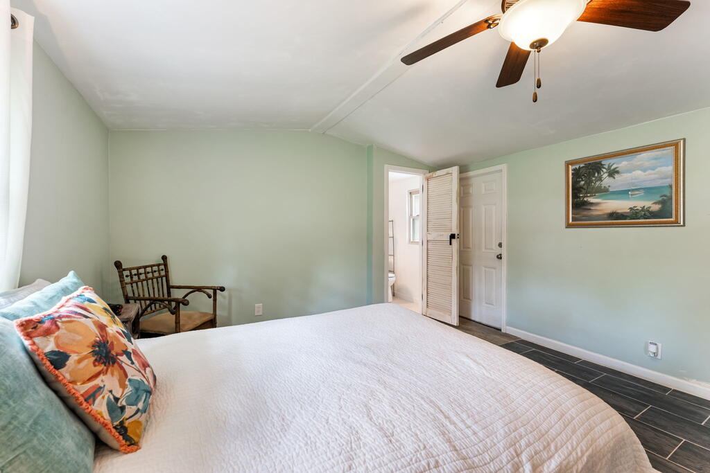Bedroom with a white quilted bed, colorful pillows, and a wooden rocking chair.