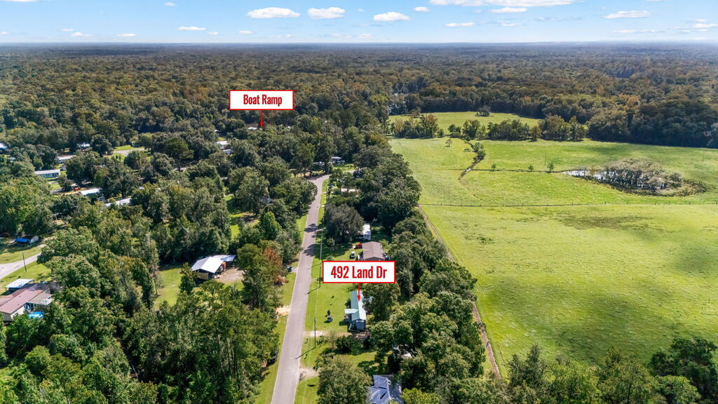 Aerial view of 492 Land Dr beside a rural road, with open fields and a nearby boat ramp marked.