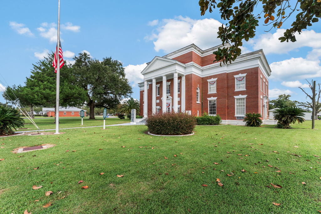 Red brick building with white columns and a broad lawn; an American flag flies nearby.