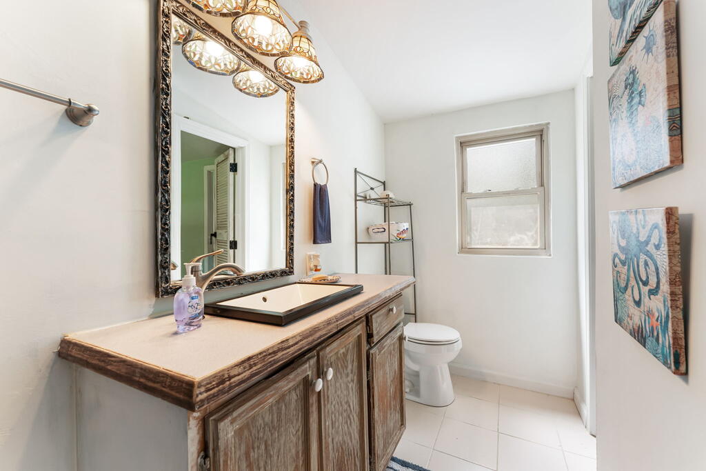 Bathroom with a rustic wood vanity, vessel sink, ornate mirror, and blue-toned wall art.