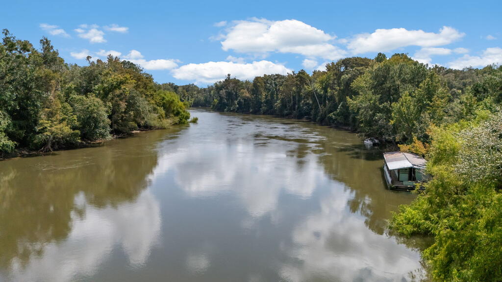 River bordered by wooded banks, with a small covered dock on the right.