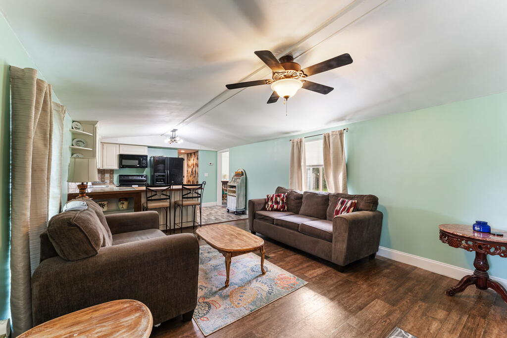 Open-plan living room with brown sofas, mint-green walls, and a kitchen breakfast bar.