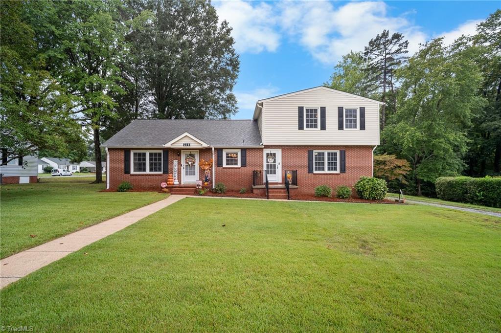 Two-story brick-and-siding house with black shutters, a broad lawn, and a walkway to the front entrance.