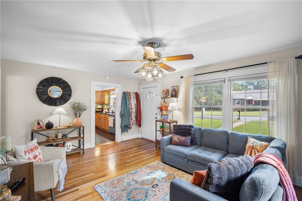 Living room with a blue sectional, hardwood floors, and large windows overlooking the street.