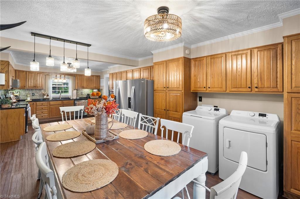 Kitchen and dining area with wood cabinetry, a stainless refrigerator, and an adjacent washer and dryer.