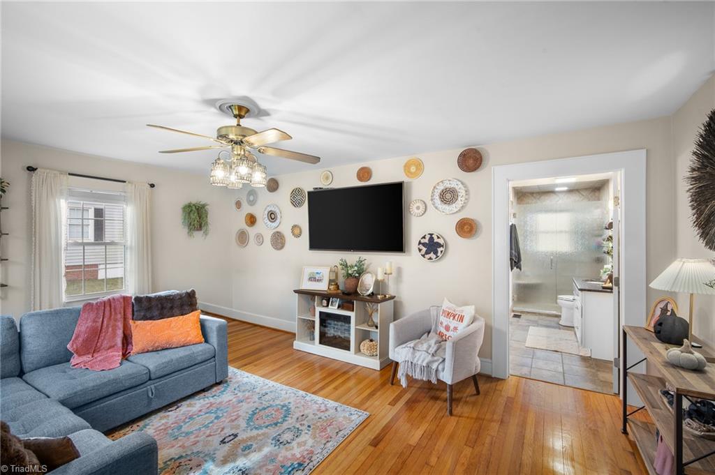 Furnished living room with blue sofas, hardwood floors, and decorative plates around a wall-mounted television.