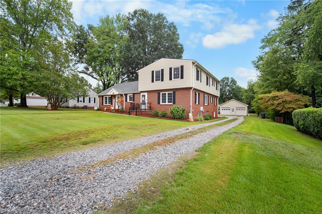 Two-story brick-and-siding home with a gravel driveway leading to a detached garage.