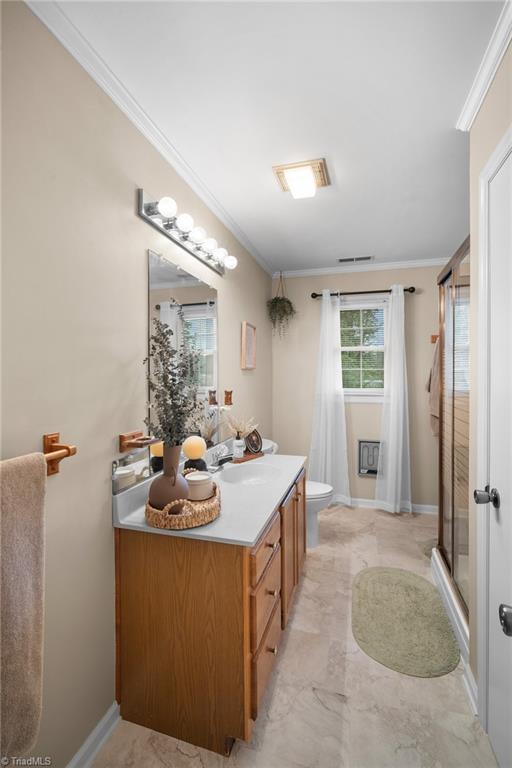 Bathroom with a wood vanity, globe-lit mirror, glass shower, and window with white curtains.