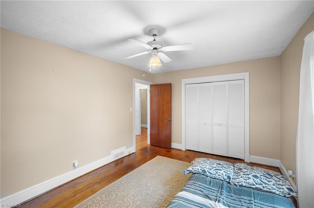 Bedroom with hardwood floors, louvered closet doors, and blue patterned bedding.