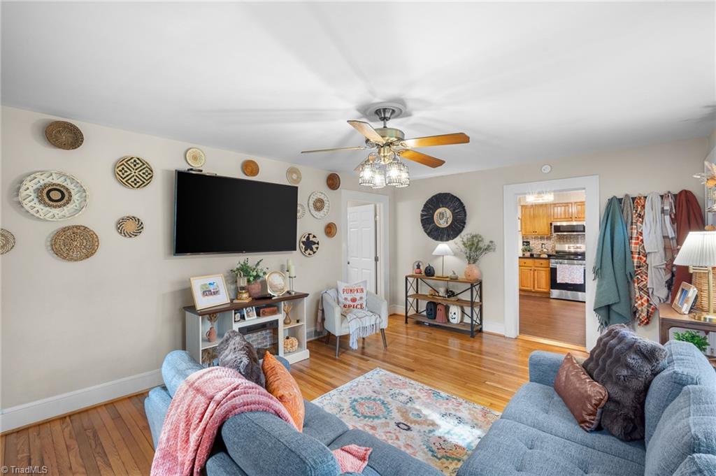Living room with blue sofas, hardwood floors, decorative wall plates, and a ceiling fan.