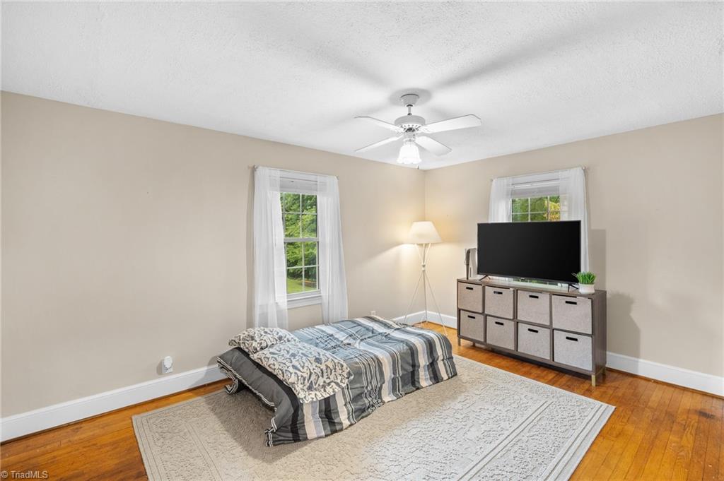 Bedroom with a low bed, two curtained windows, and a TV on a cube-storage unit.