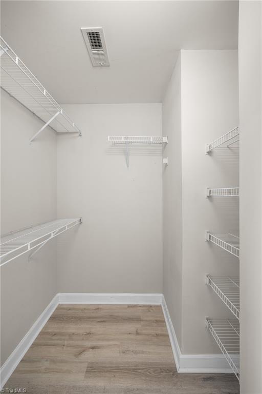 Walk-in closet with white wire shelving and wood-look plank flooring.