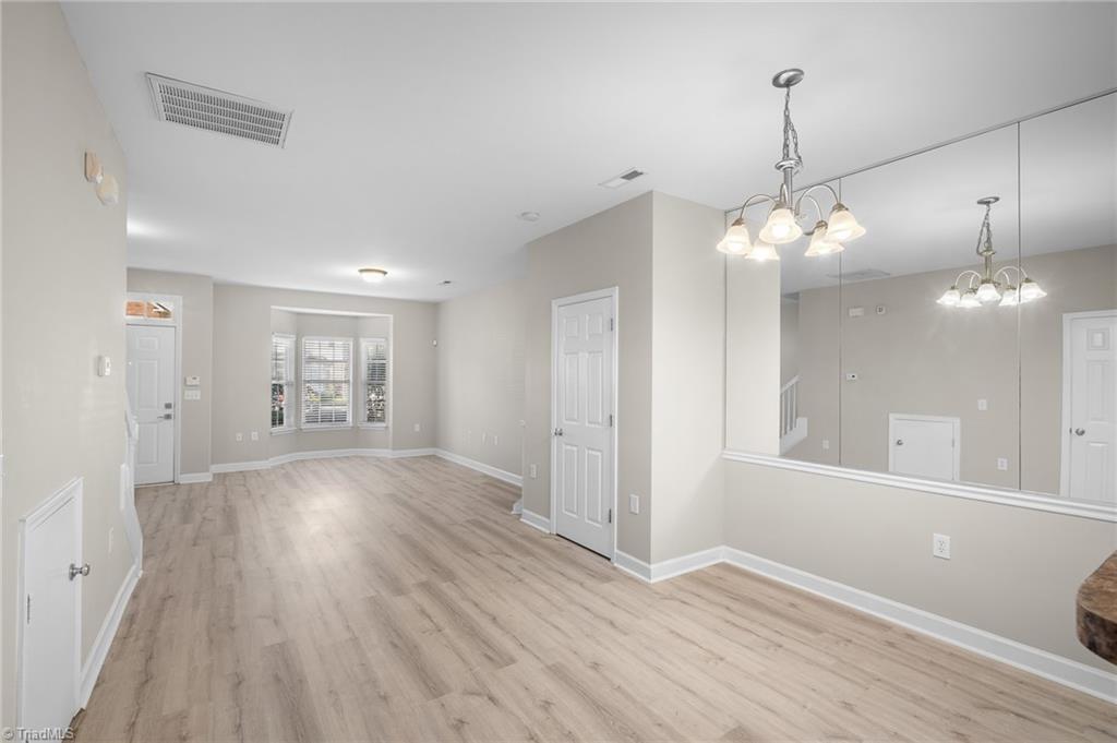 Unfurnished interior with light wood-look flooring, a bay window, and a large mirrored wall.