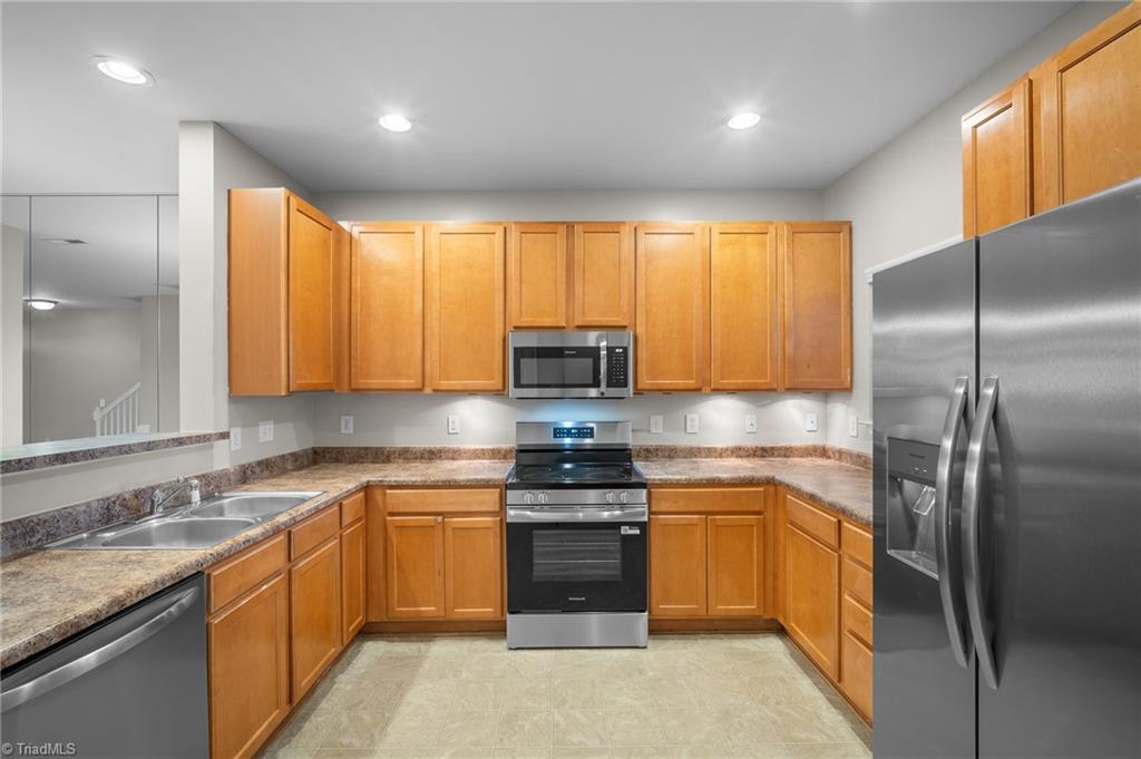 Kitchen with warm wood cabinets, stainless steel appliances, and a double-basin sink.