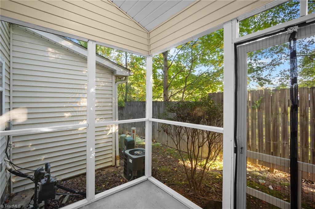 Screened porch with white framing overlooking a fenced, leafy yard.