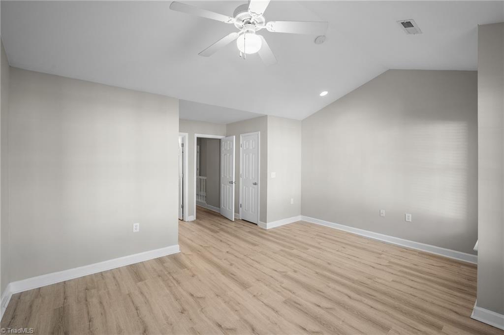 Empty room with light wood-look flooring, neutral walls, and a ceiling fan.