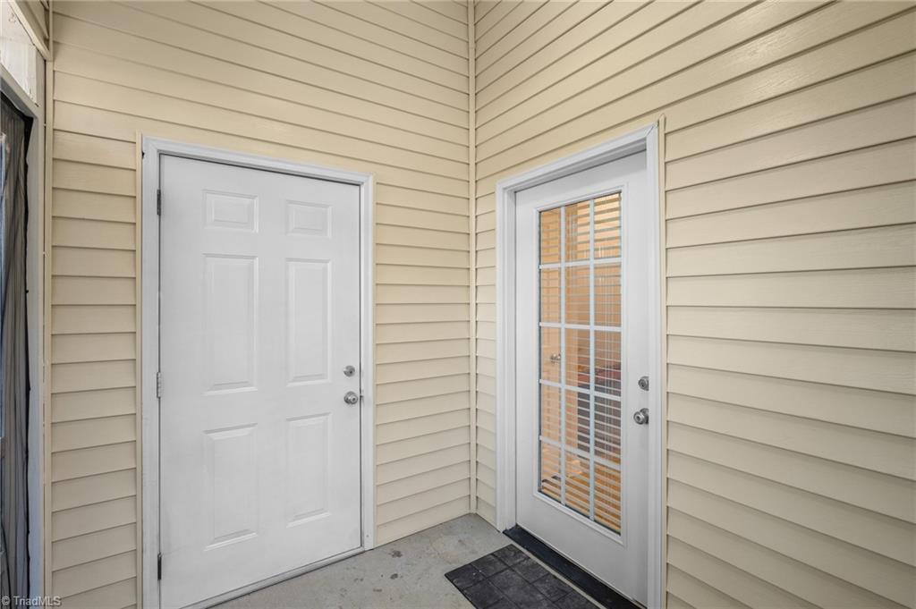 Home entry with a white front door beside a glass-paneled door and beige siding.