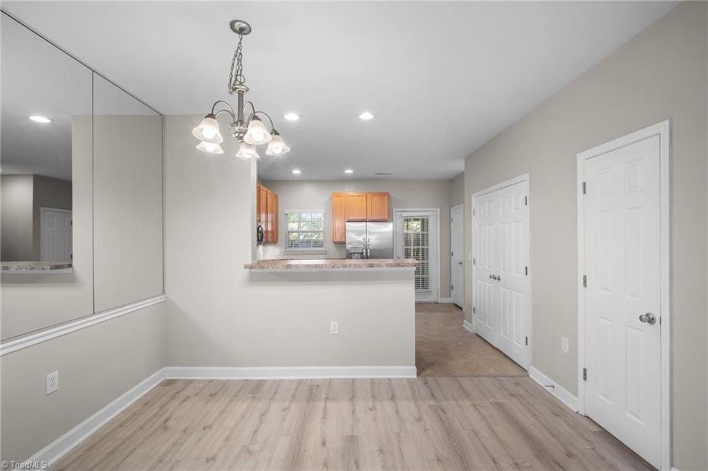 Unfurnished dining area with a mirrored wall, chandelier, and breakfast bar opening to the kitchen.
