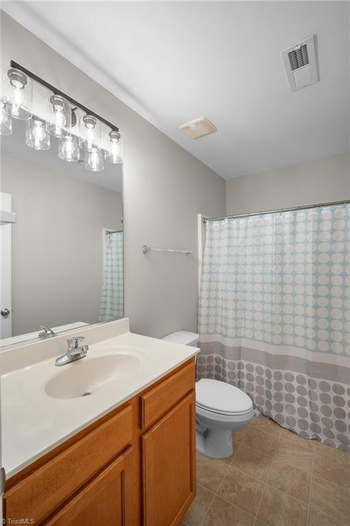 Bathroom with a wood vanity, white sink, and pale blue patterned shower curtain.