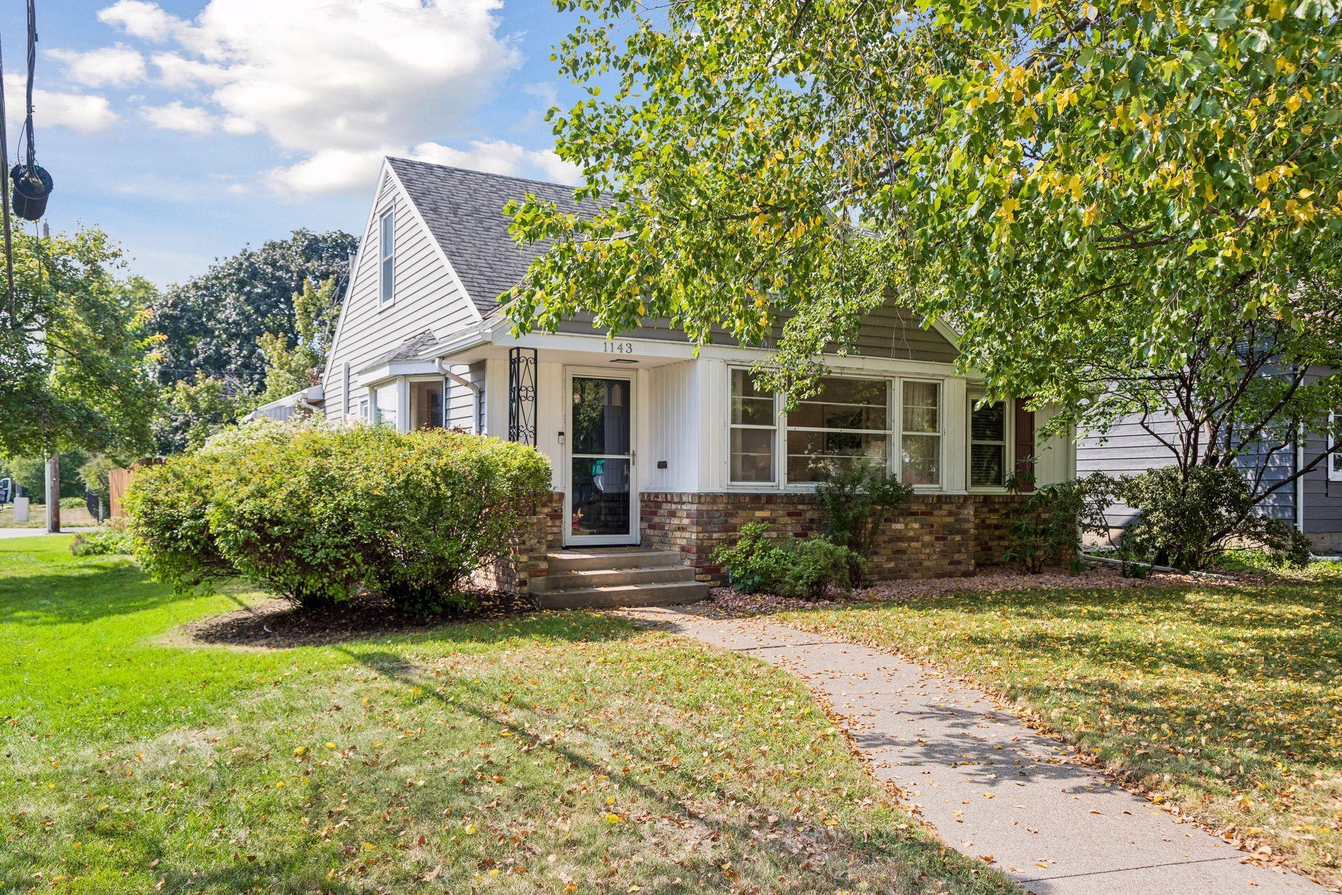 House at 1143 Cleveland Avenue S with white siding, a brick facade, and a tree-shaded front yard.