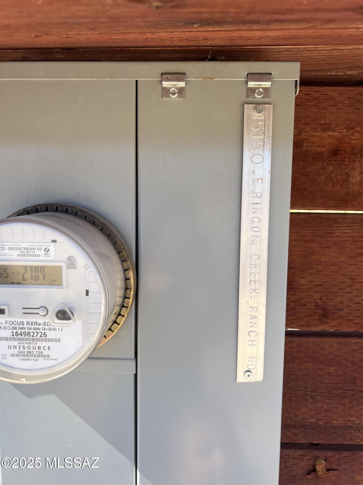 Outdoor electrical meter and panel with a metal Rincon Creek Ranch Road address plaque.
