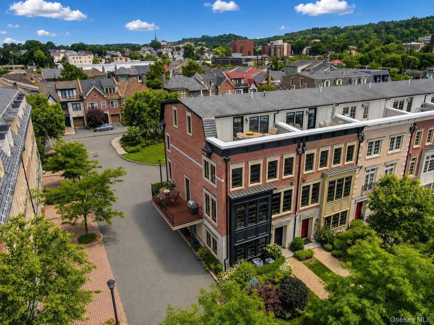 Aerial view of 143 W Main Street's brick facade, rooftop terrace, and surrounding neighborhood.