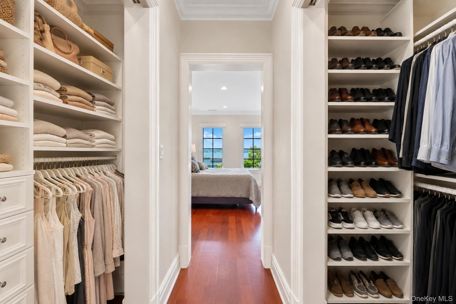 Walk-in closet with built-in clothing and shoe storage, opening to a bedroom with water views.