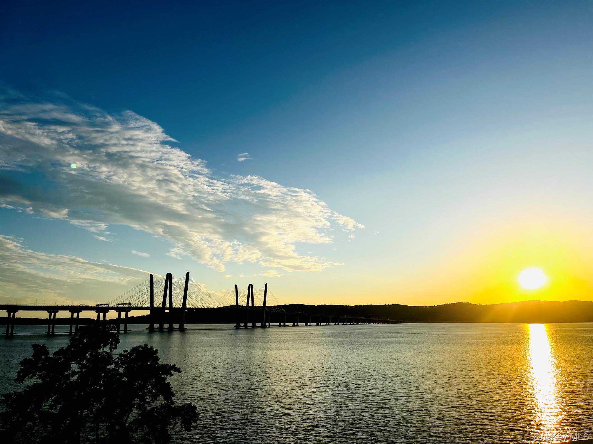 Cable-stayed bridge over the water at sunset, with sunlight reflecting across the surface.