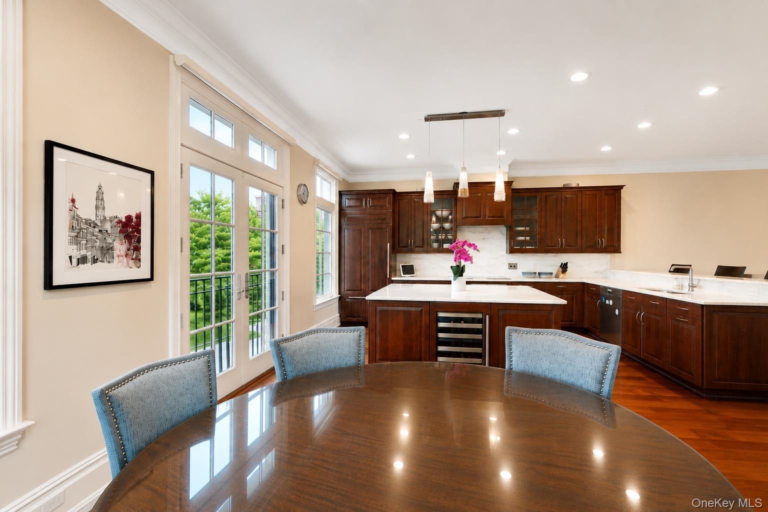 Kitchen and dining area with dark wood cabinets, a white island, French doors, and a round table.
