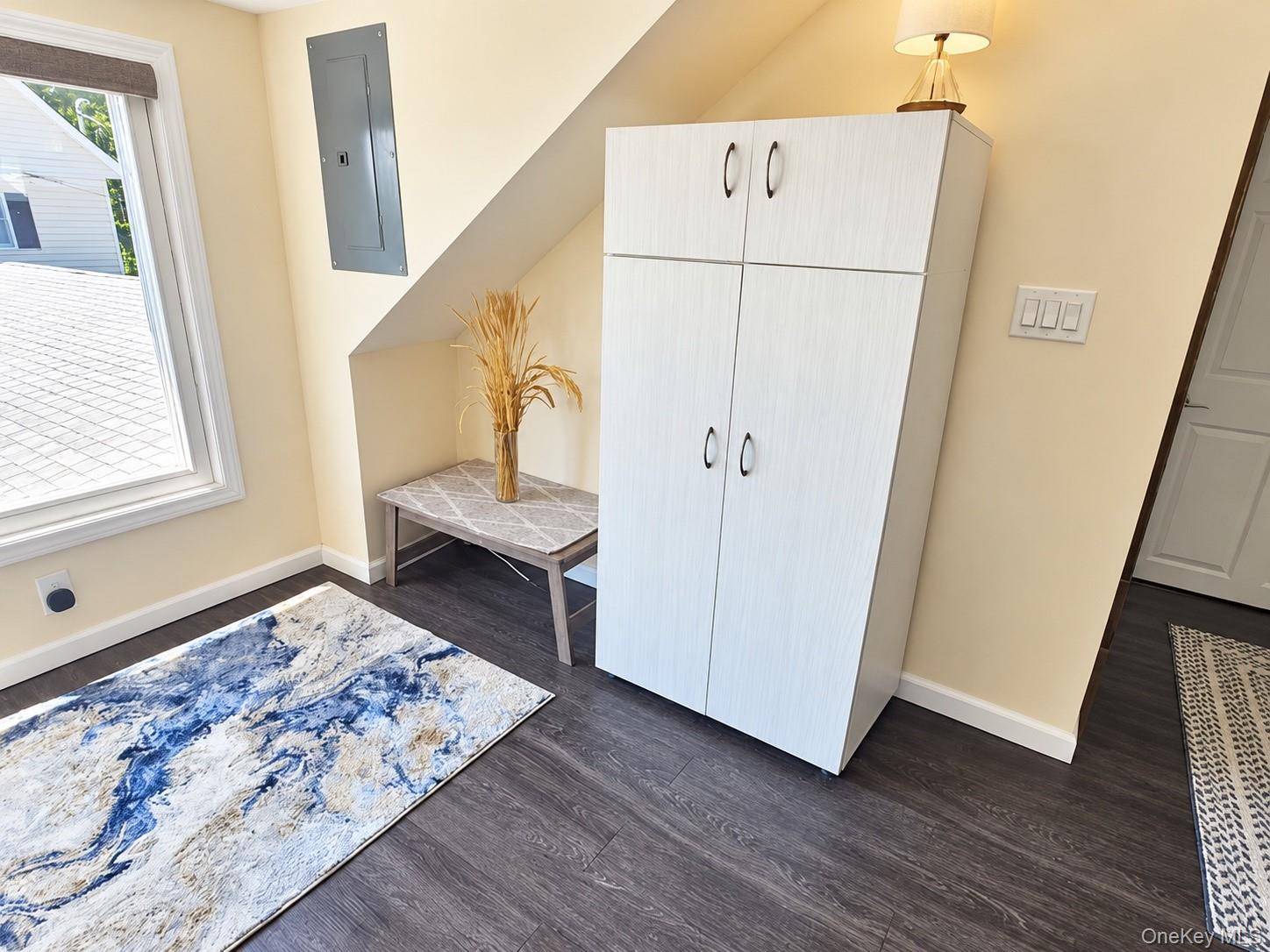 Entry area with a tall white storage cabinet, small table, and patterned rugs.