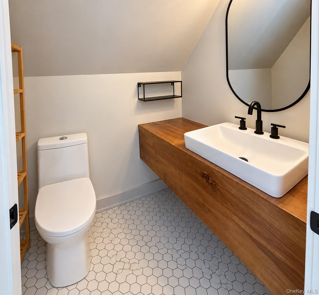 Bathroom with a wood floating vanity, vessel sink, toilet, and hexagonal tile floor.