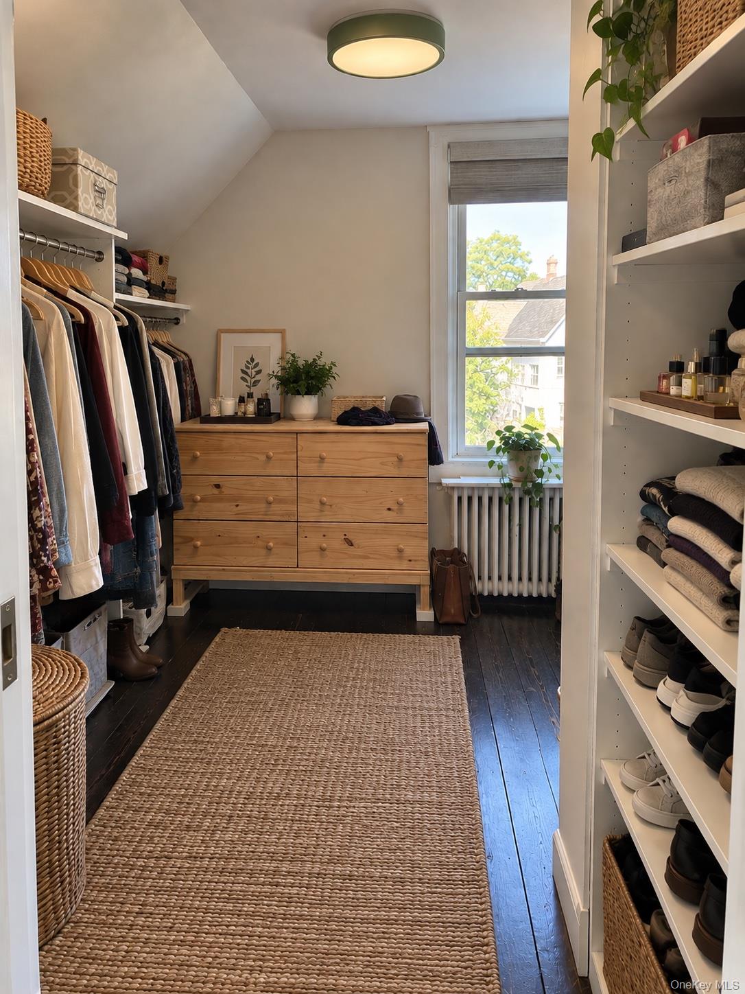 Walk-in closet with open clothing and shoe shelves, a pine dresser, and a window.