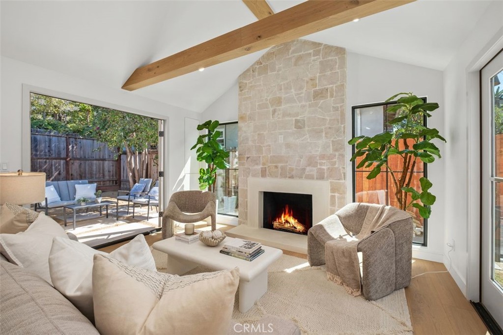 Living room with a tall stone fireplace, exposed wood beam, and sliding doors to a patio.