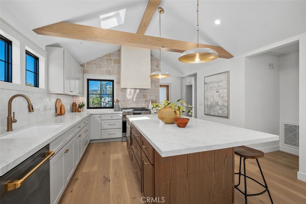 Bright kitchen with a large wood-paneled island, white cabinetry, and brass fixtures.