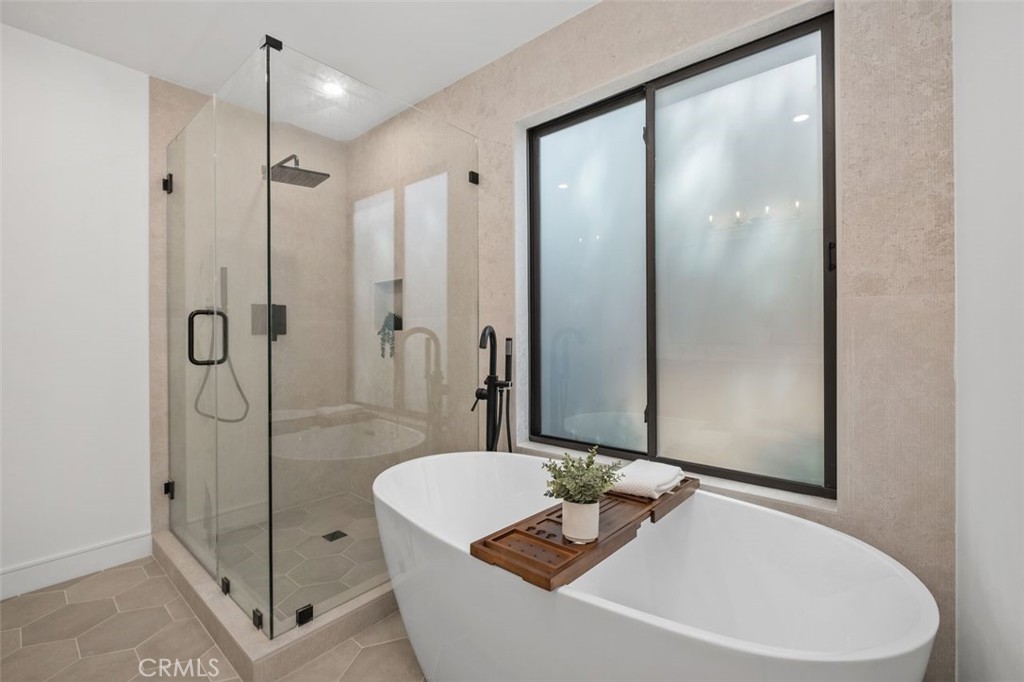 Modern bathroom with a freestanding soaking tub, wooden bath tray, and glass-enclosed shower.