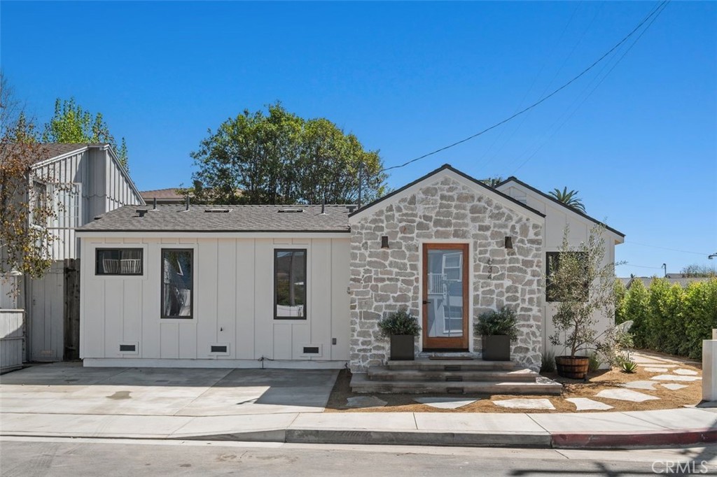 Street view of a single-story home with a stone front entry and white siding.