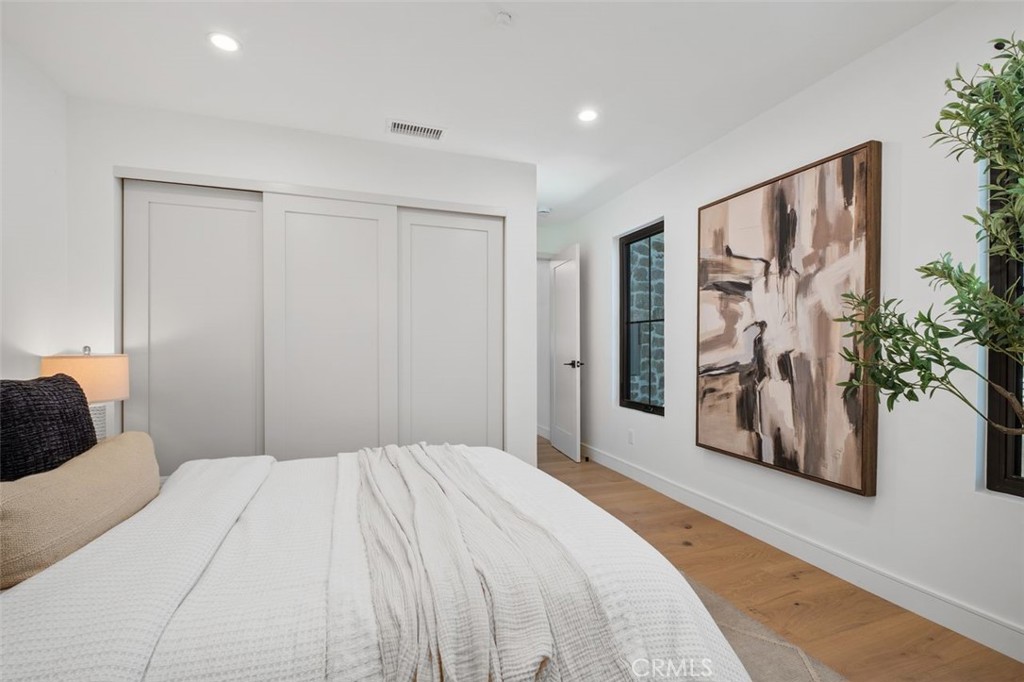 Staged bedroom with a white bed, sliding closet doors, and a large abstract painting.