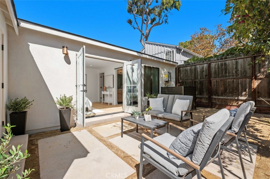 Furnished courtyard patio with gray lounge seating, a low table, and open folding doors to the home.