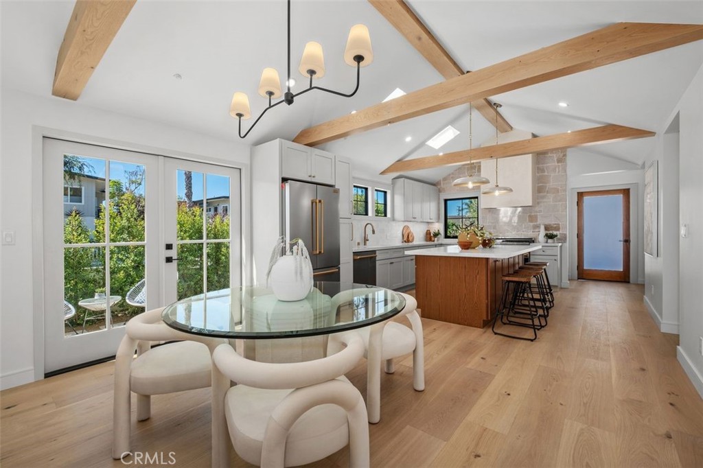 Staged kitchen and dining area with exposed wood beams, a wood-front island, and French doors.