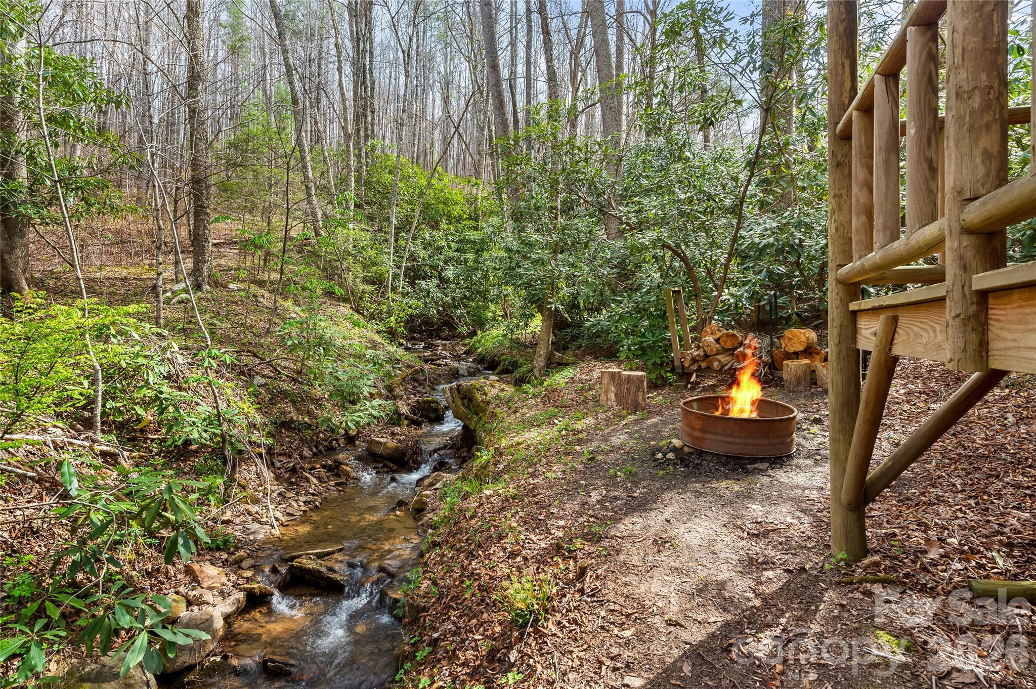 Wooded creekside fire pit beside a timber deck at 70 Fox Run.