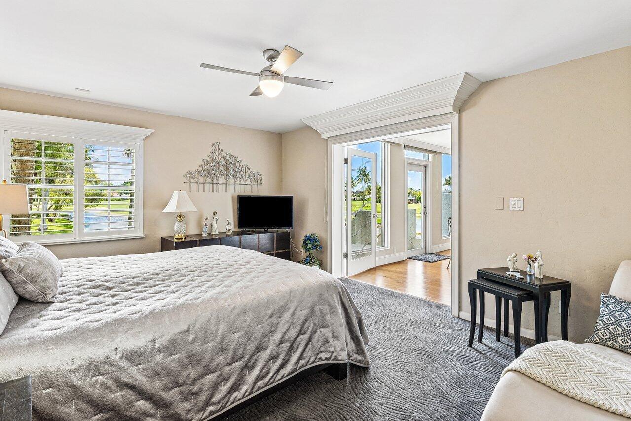 Bedroom with a large bed, shuttered windows, and French doors opening to a sunny adjoining space.