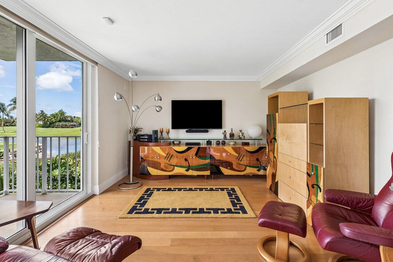 Living room with colorful wooden entertainment furniture and burgundy leather seating, opening onto a lake-view balcony.